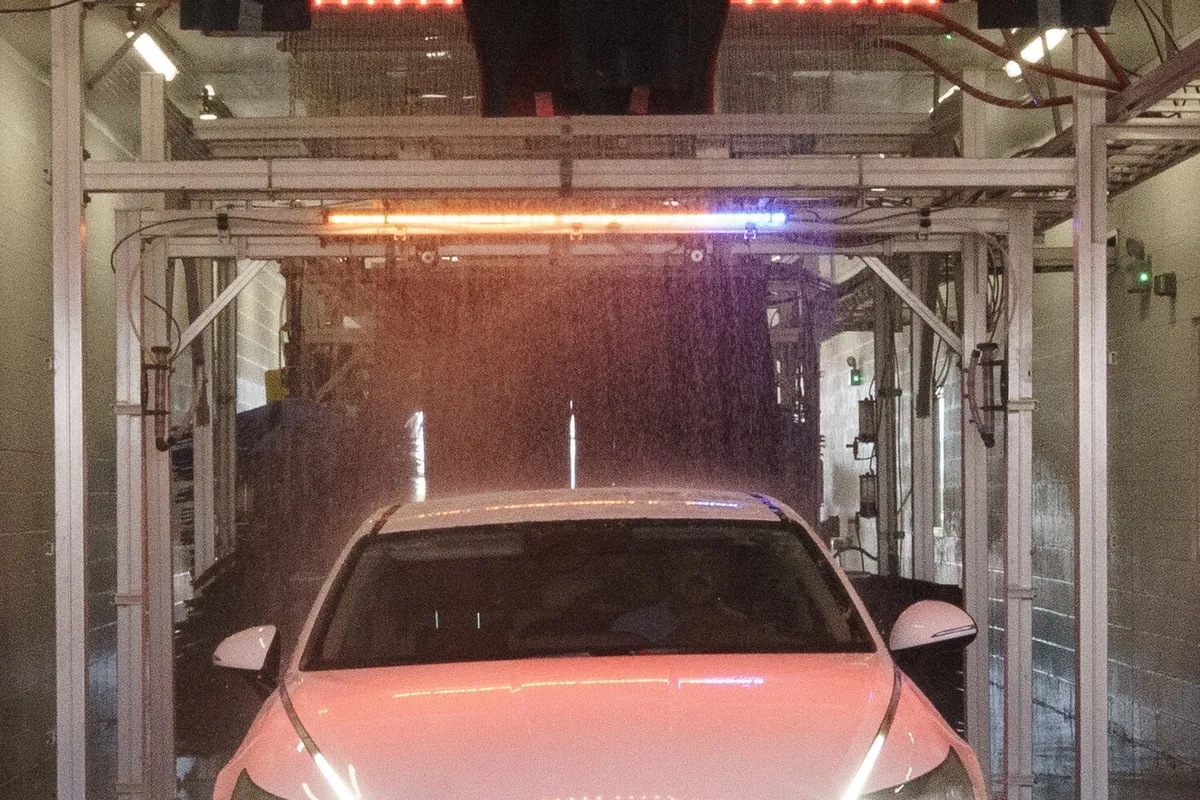 Car hood and windscreen under the overhead spray arch in the wash bay