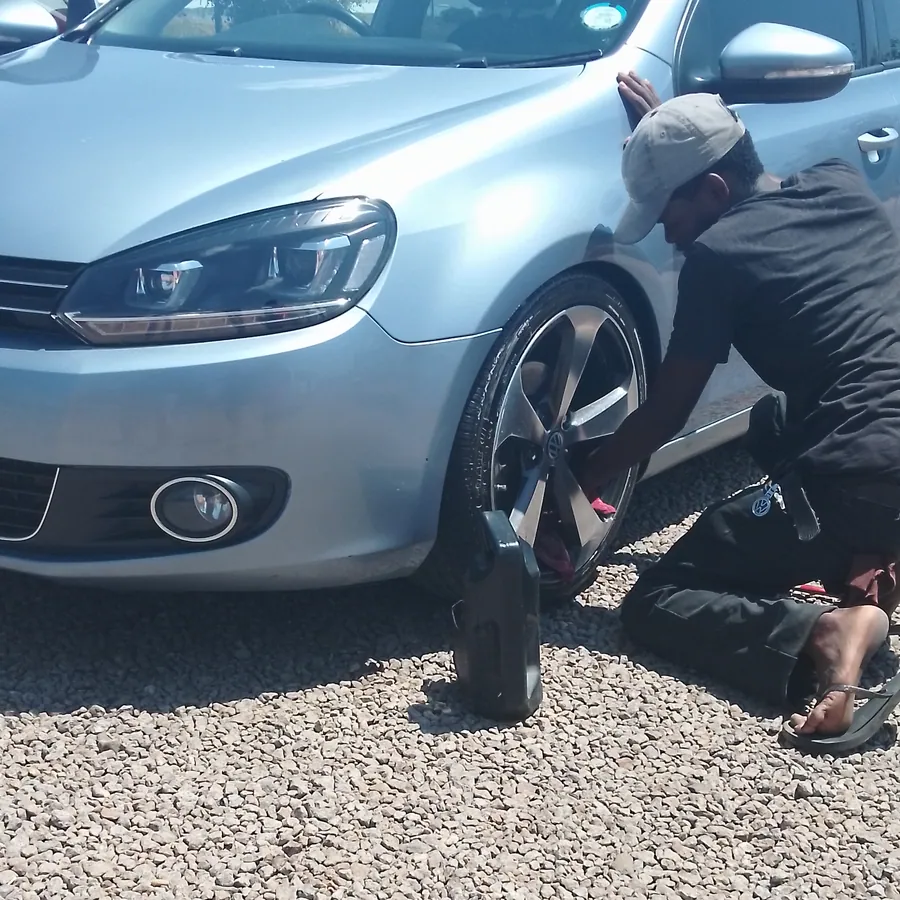 Technician crouched at a wheel arch during an exterior clean