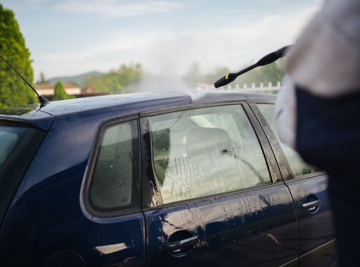 A pressure washer rinsing down the flank of a hatchback