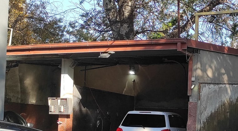 An open wash bay under the canopy, lance on its hook and a car pulled in