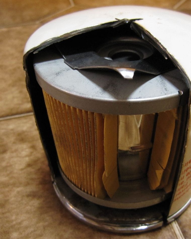 An engine oil filter cut open to show its pleated paper element and inner steel core.