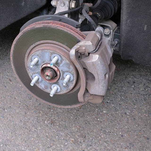 A closer view of a front disc brake with the wheel removed: the caliper clamped over a vented rotor.