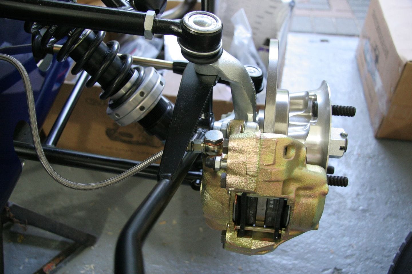 Brake pipes and flexible hoses being fitted and tightened along a car's chassis rail.