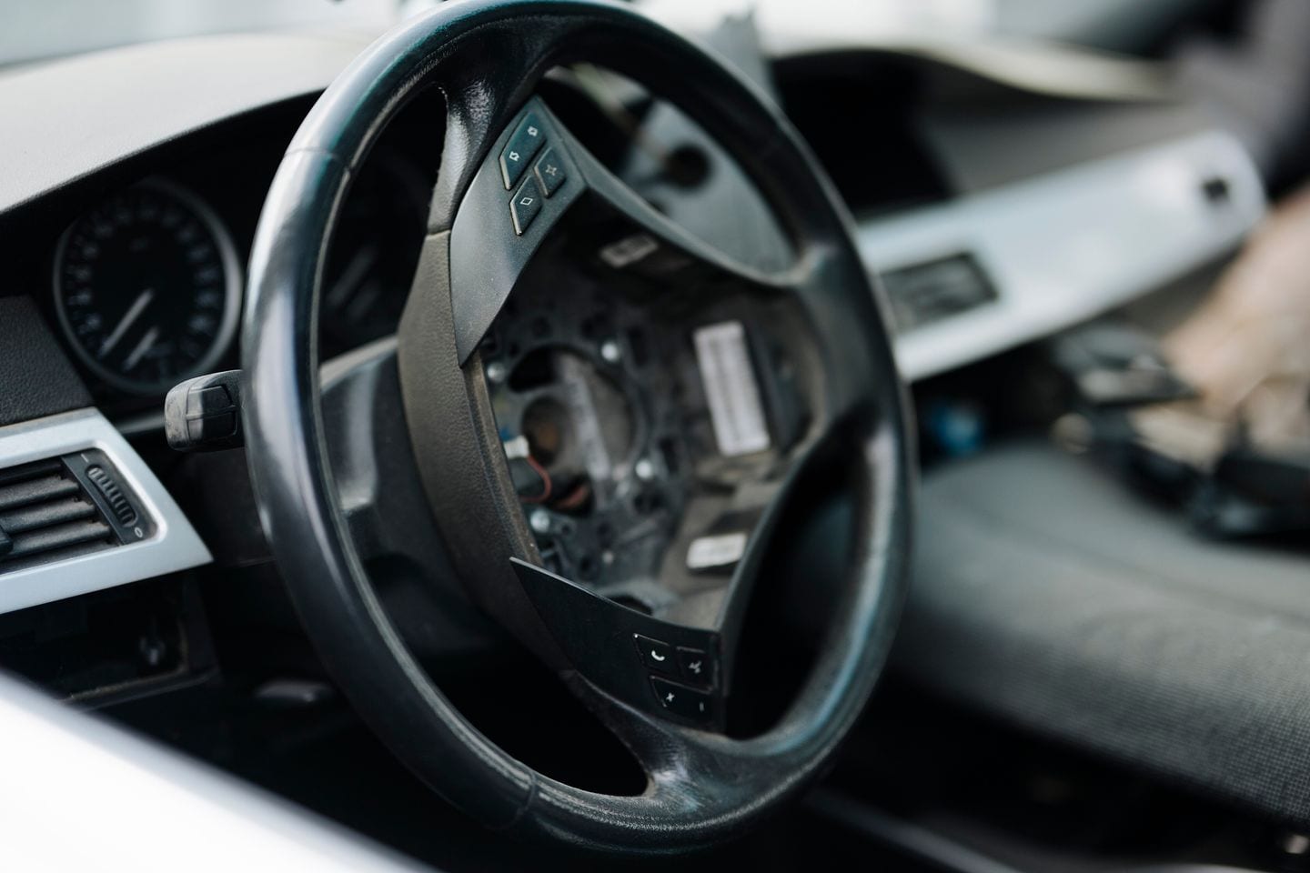 A car interior with the steering wheel in place and parts of the dashboard removed during work.