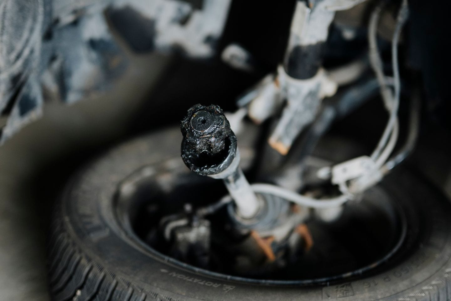 A car suspension assembly with the wheel and tire still fitted, showing damage to the components.