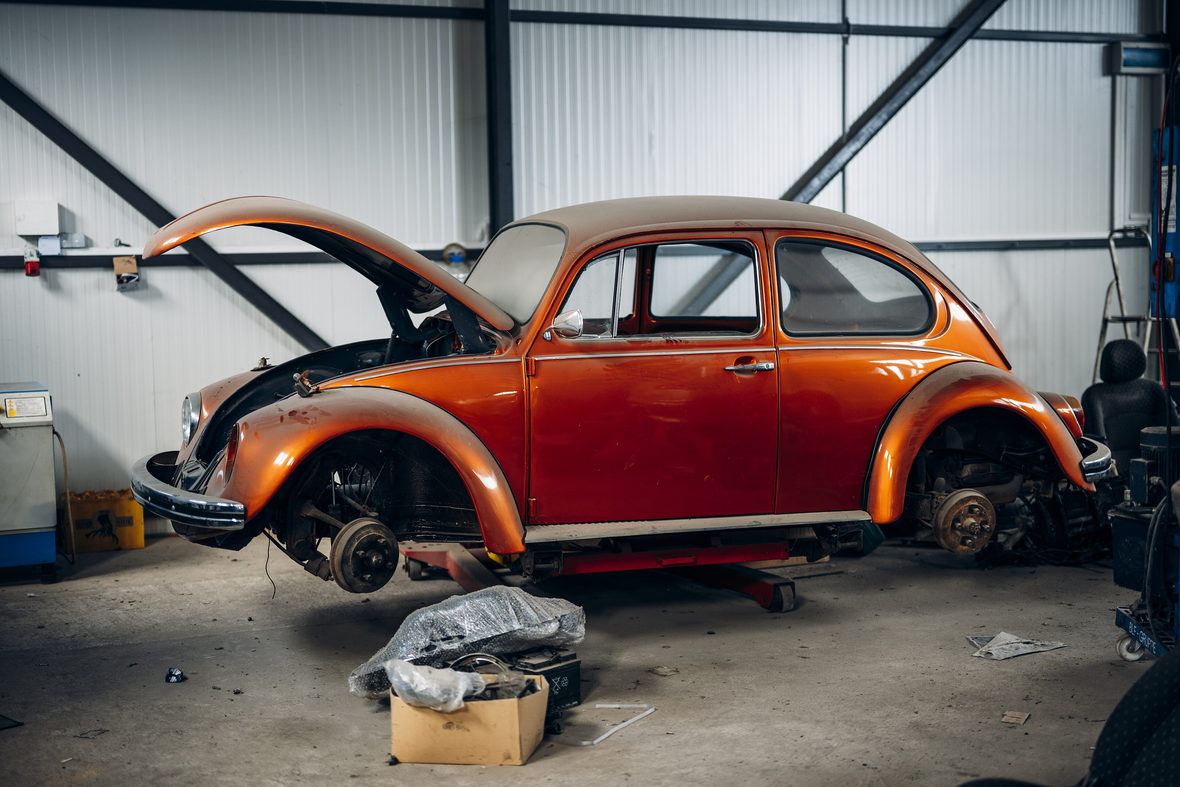 A partly stripped car standing on a workshop floor during a long restoration.