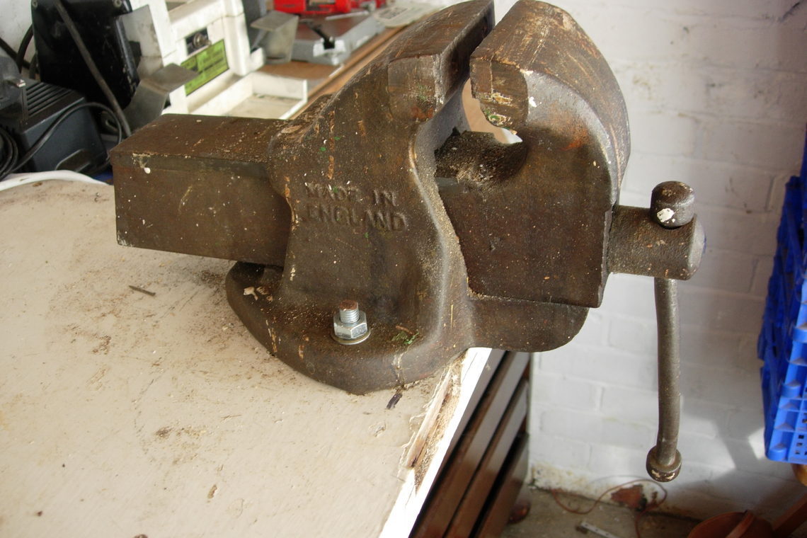 A bench vice clamped to the edge of a workshop bench.