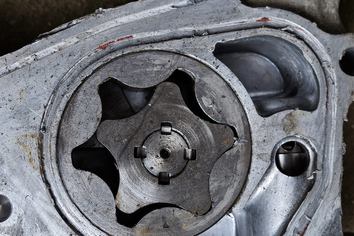 An oil pump removed from an engine and set down on a bench.