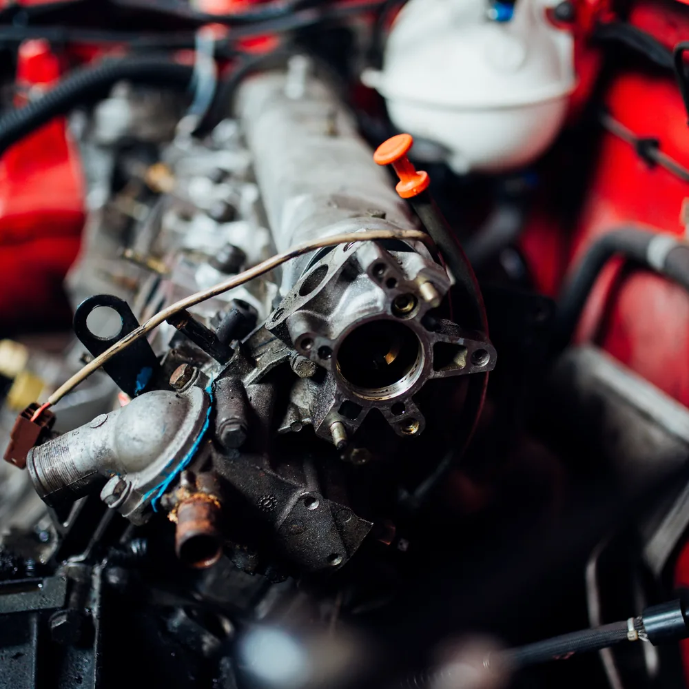 Engine bay of a red car opened up during a mechanical inspection