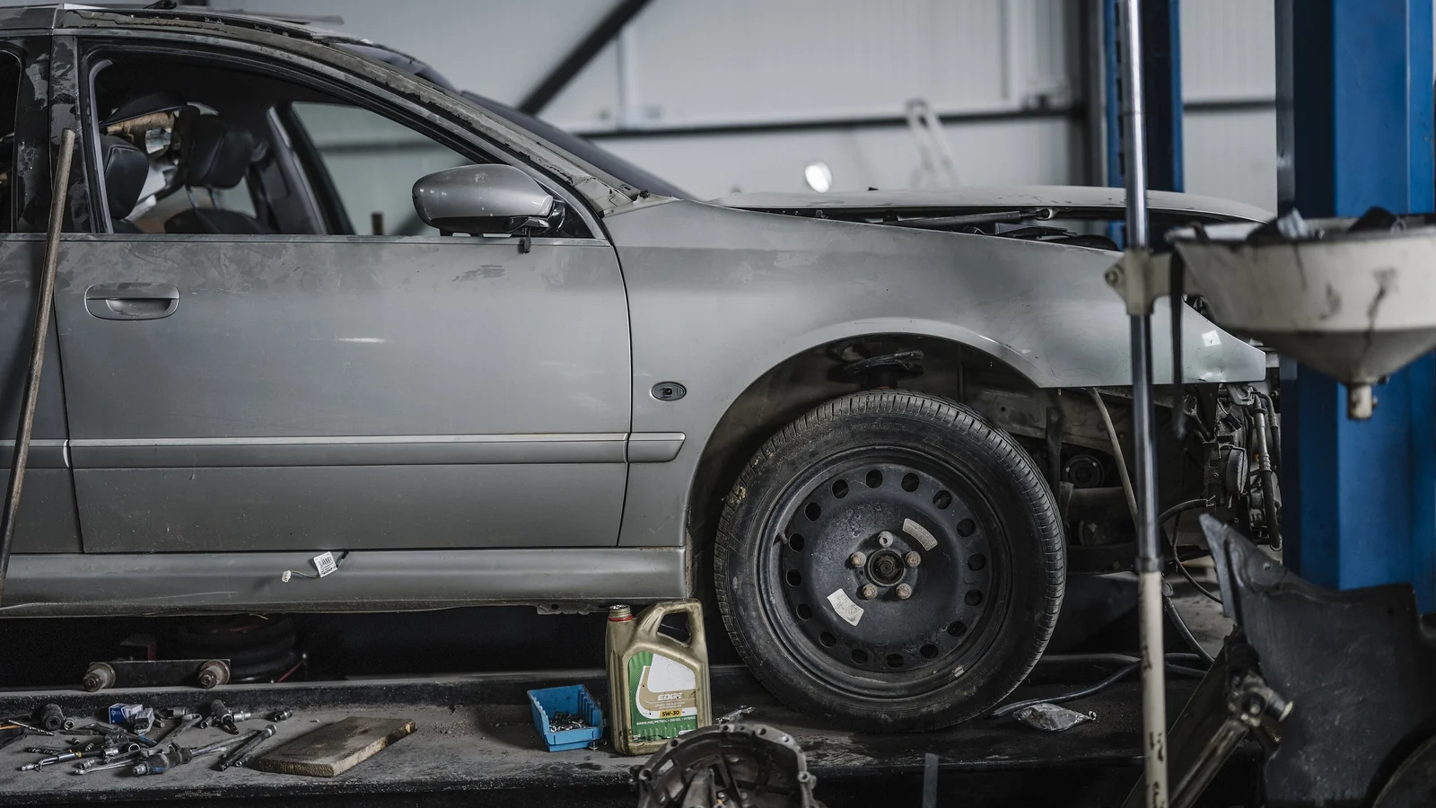 A car raised on a two-post lift in the service bay
