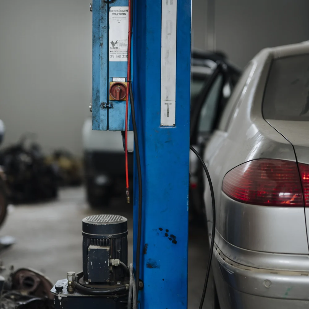 A car raised on a two-post lift in the service bay