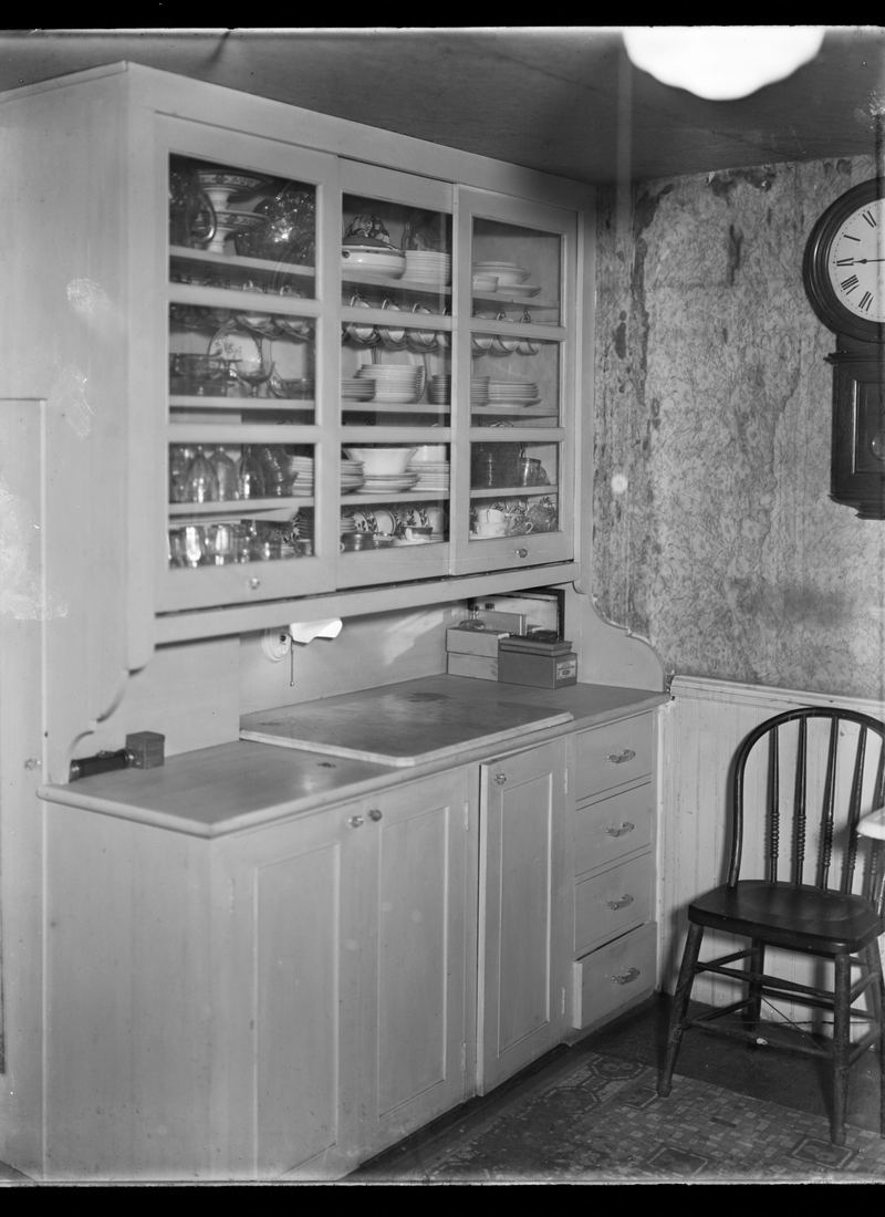 A plain working kitchen with a black range, a deep sink and open shelving along one wall.