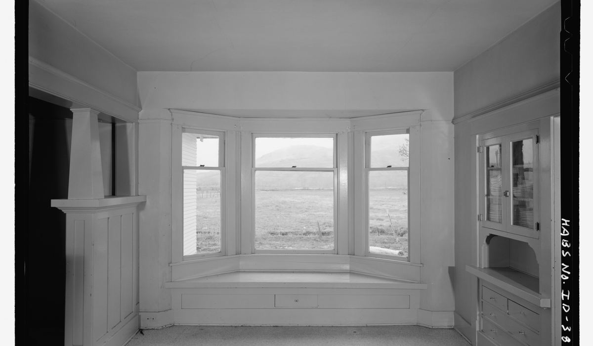 A dining room bay window seen from inside, looking west into bright daylight across the sill.
