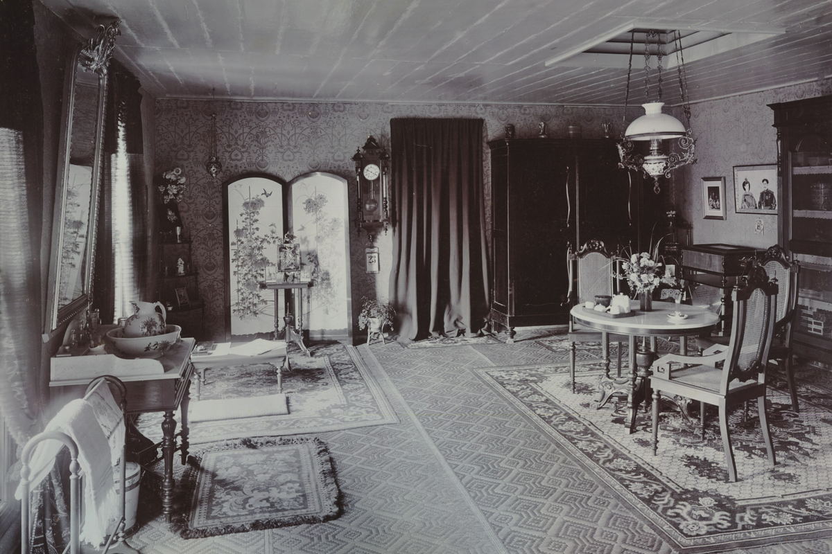 A long verandah room with a tiled floor, shuttered openings down one side and cane furniture at the far end.