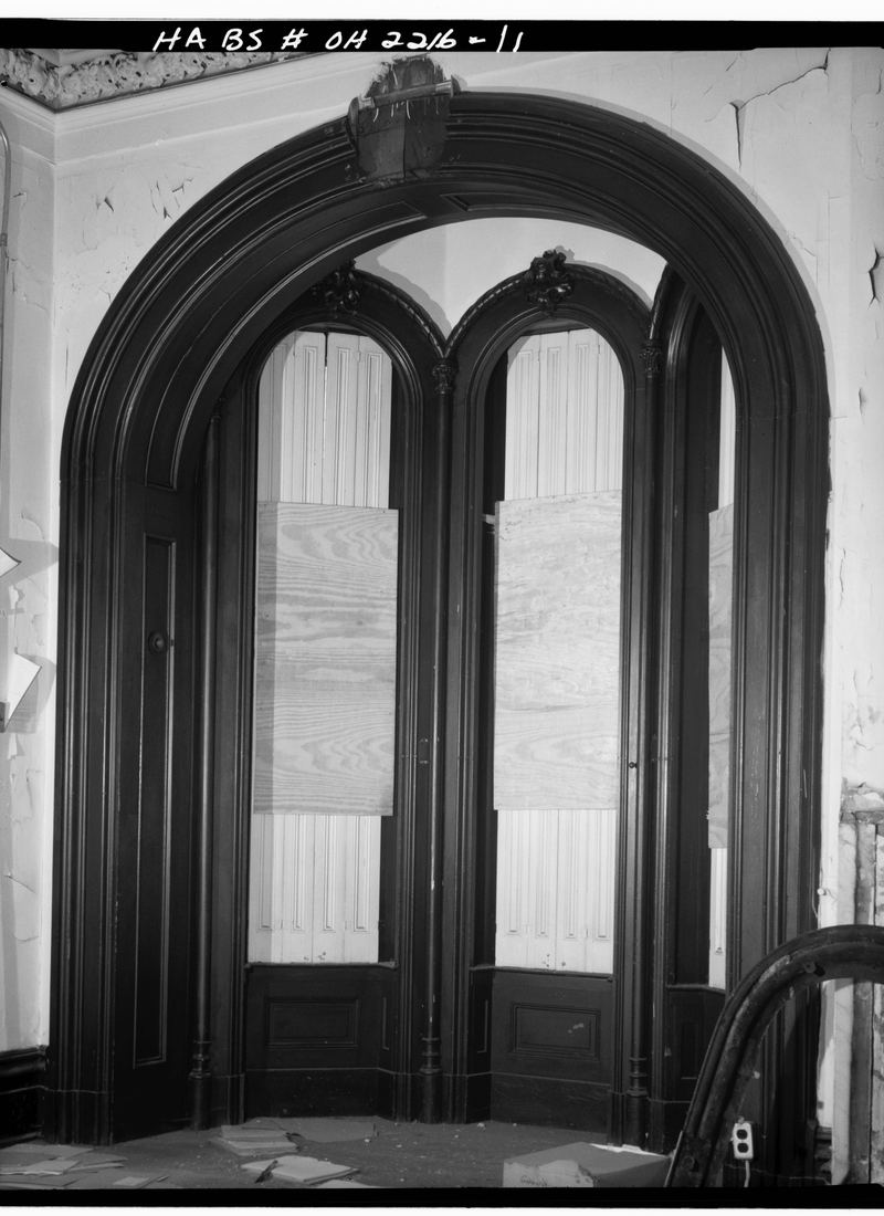 A tall bay window in an upstairs room, photographed square on with the shutters folded back.