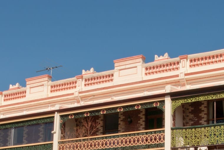 A brick terrace with decorated parapets and first-floor verandas trimmed in cast-iron lacework.