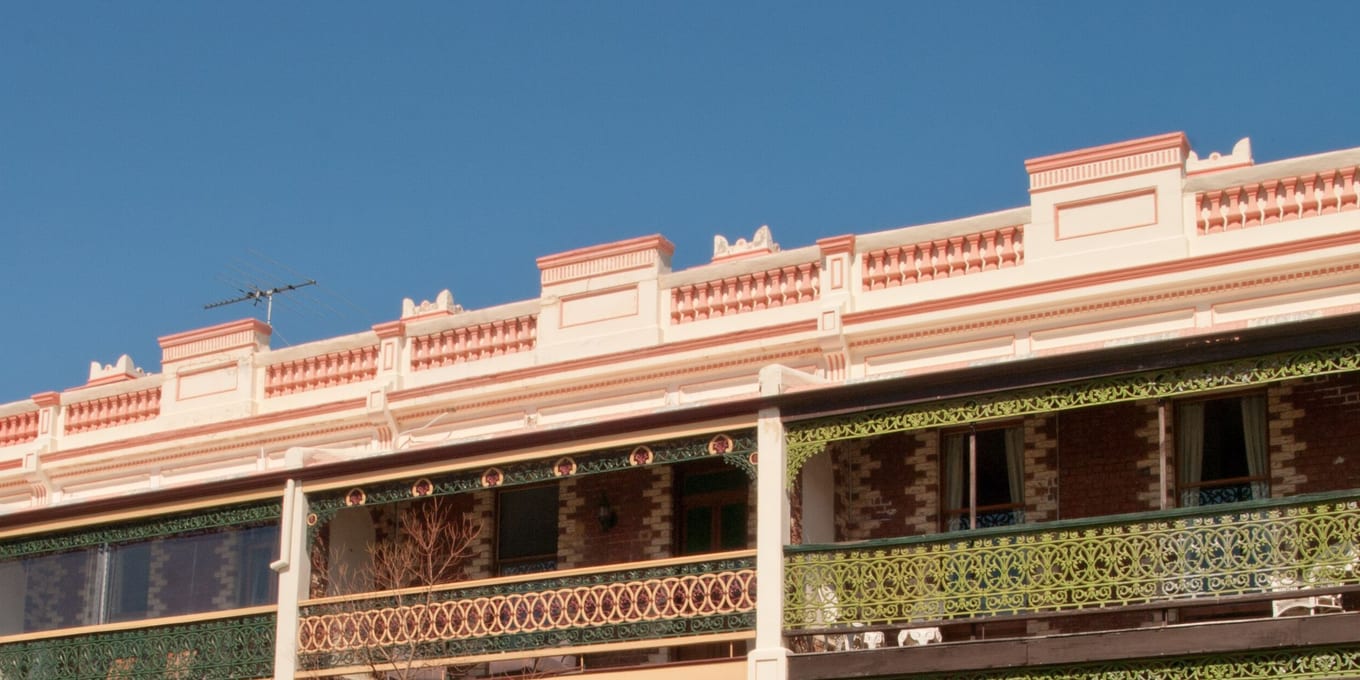 A brick terrace with decorated parapets and first-floor verandas trimmed in cast-iron lacework.