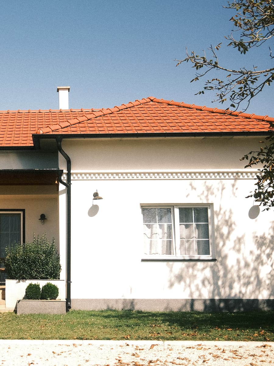 A modern house with a red tiled roof standing behind a landscaped front garden under a clear sky.