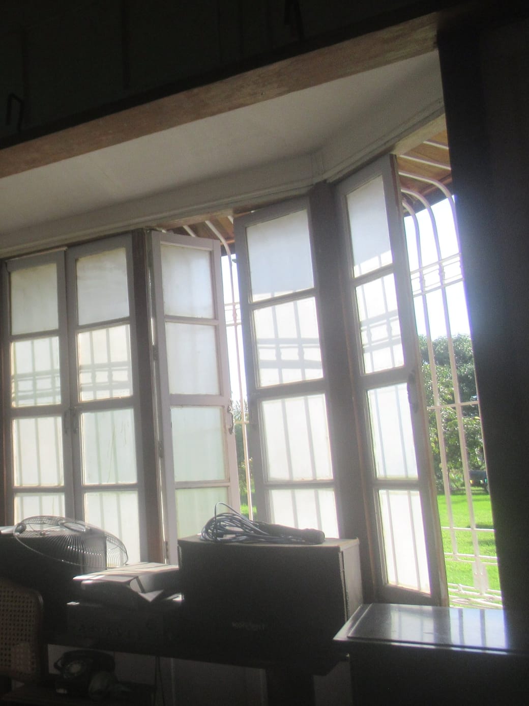 Tall casement windows in a corner bay, one standing open onto a green lawn beyond.