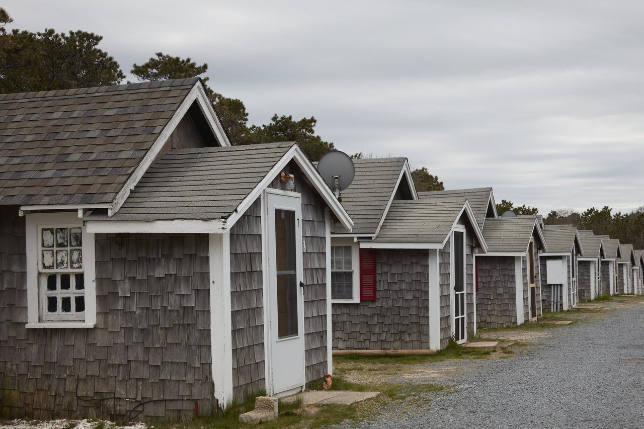 A row of small shingled cottages set among dune grass near the beach