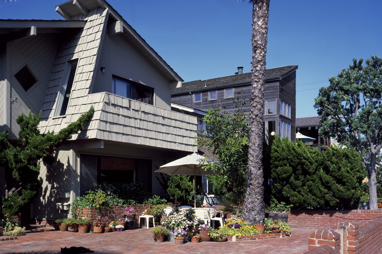 Seabreeze Shingle House — a cedar-shingled beach house above a brick courtyard of potted flowers