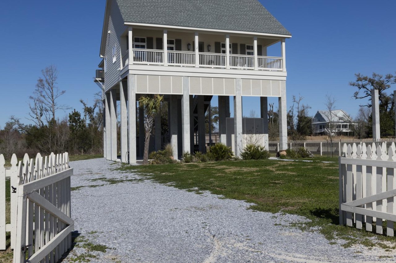 Tidewater Beach House — raised timber beach house with a wraparound porch on the shore