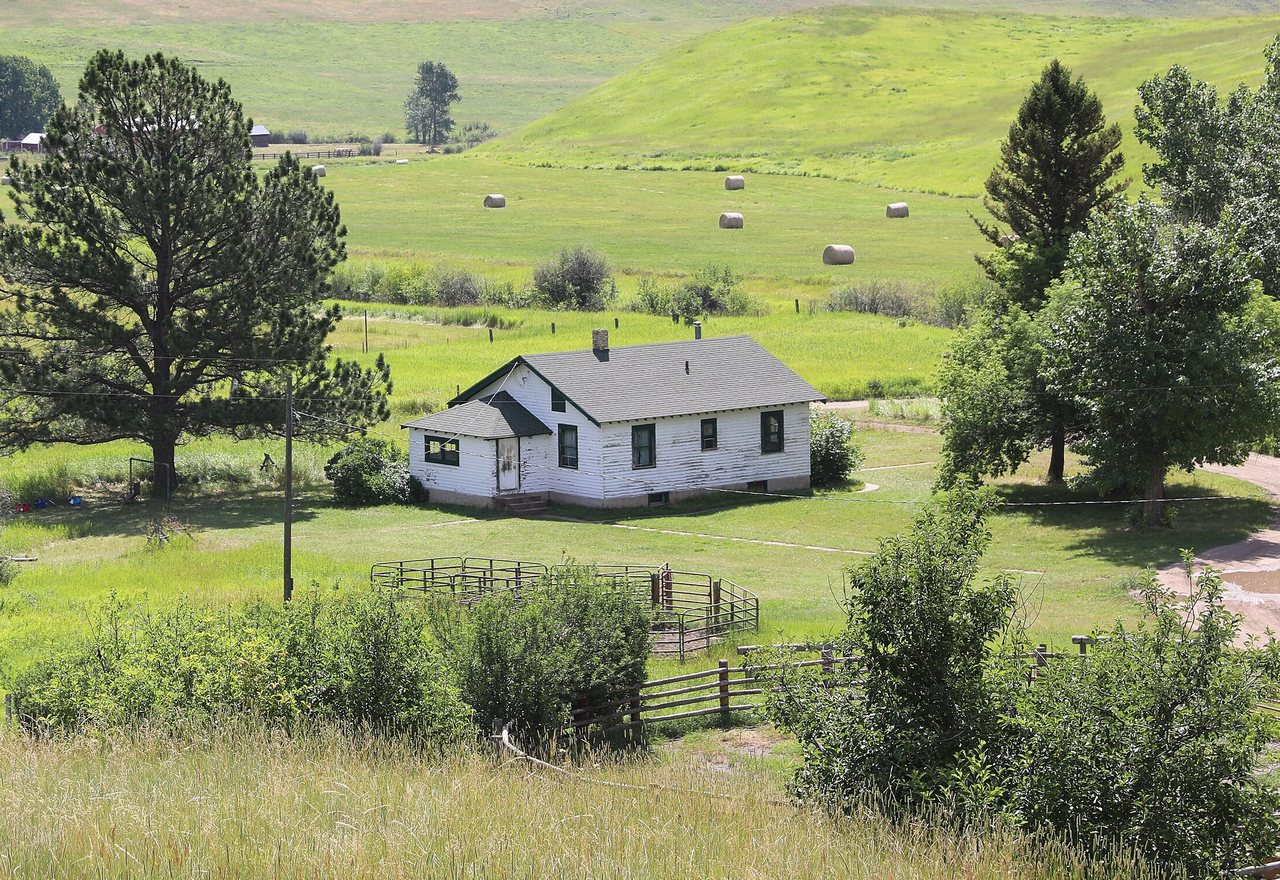 Prairie Farmhouse — a white timber farmhouse standing among hay meadows below wooded hills, Greenhaven, OR