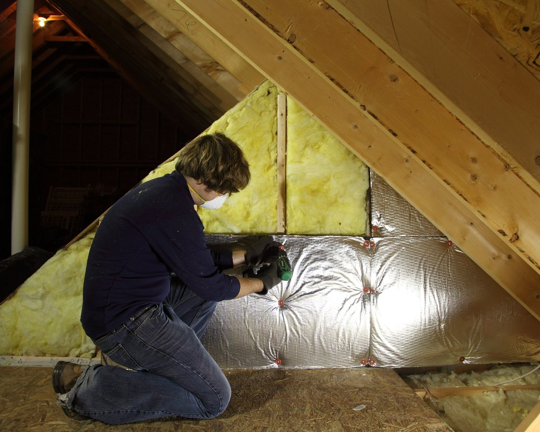 Mineral-wool and radiant-barrier insulation being fitted into a house attic