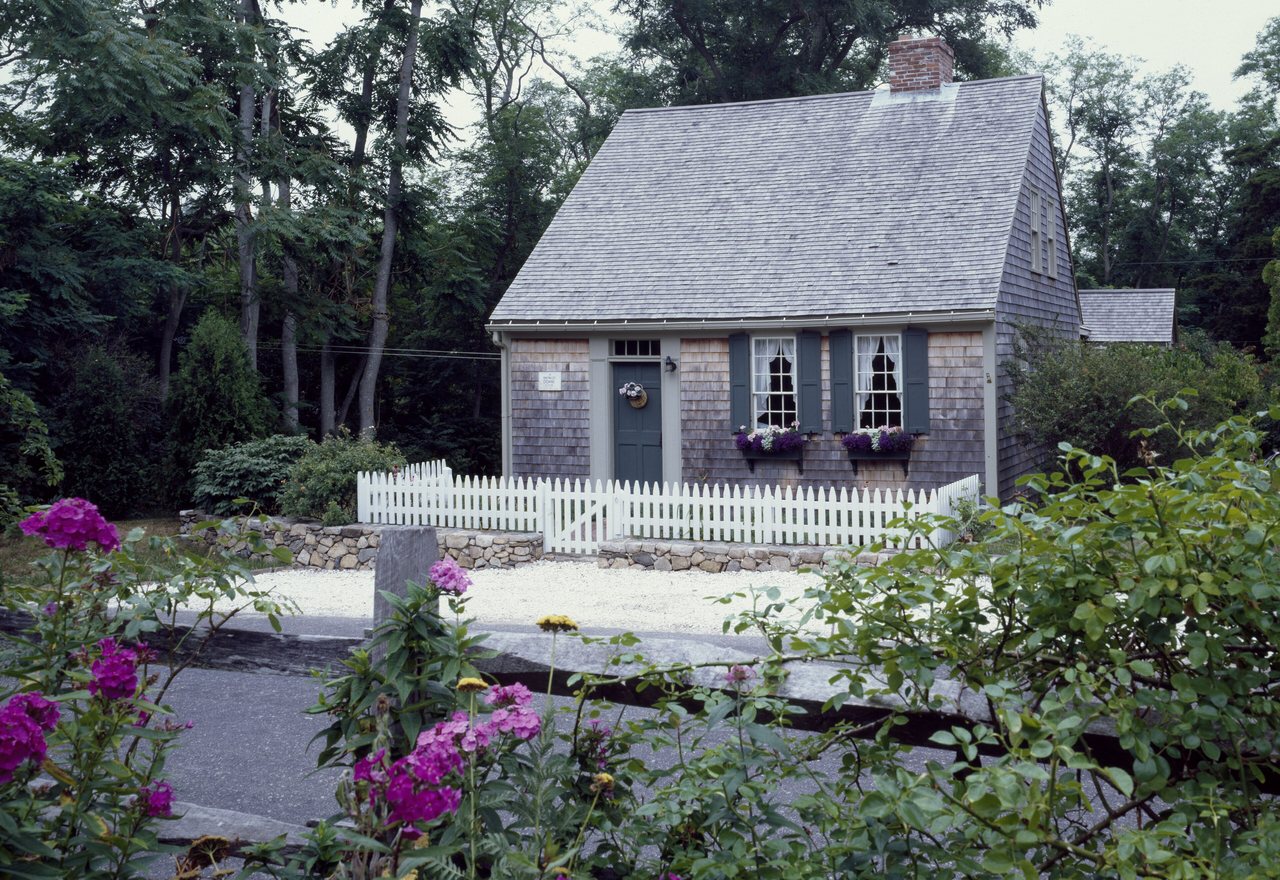 Willow Cottage — a shingled cape cottage behind a white picket fence and flowering borders, Cedar Hollow, OR