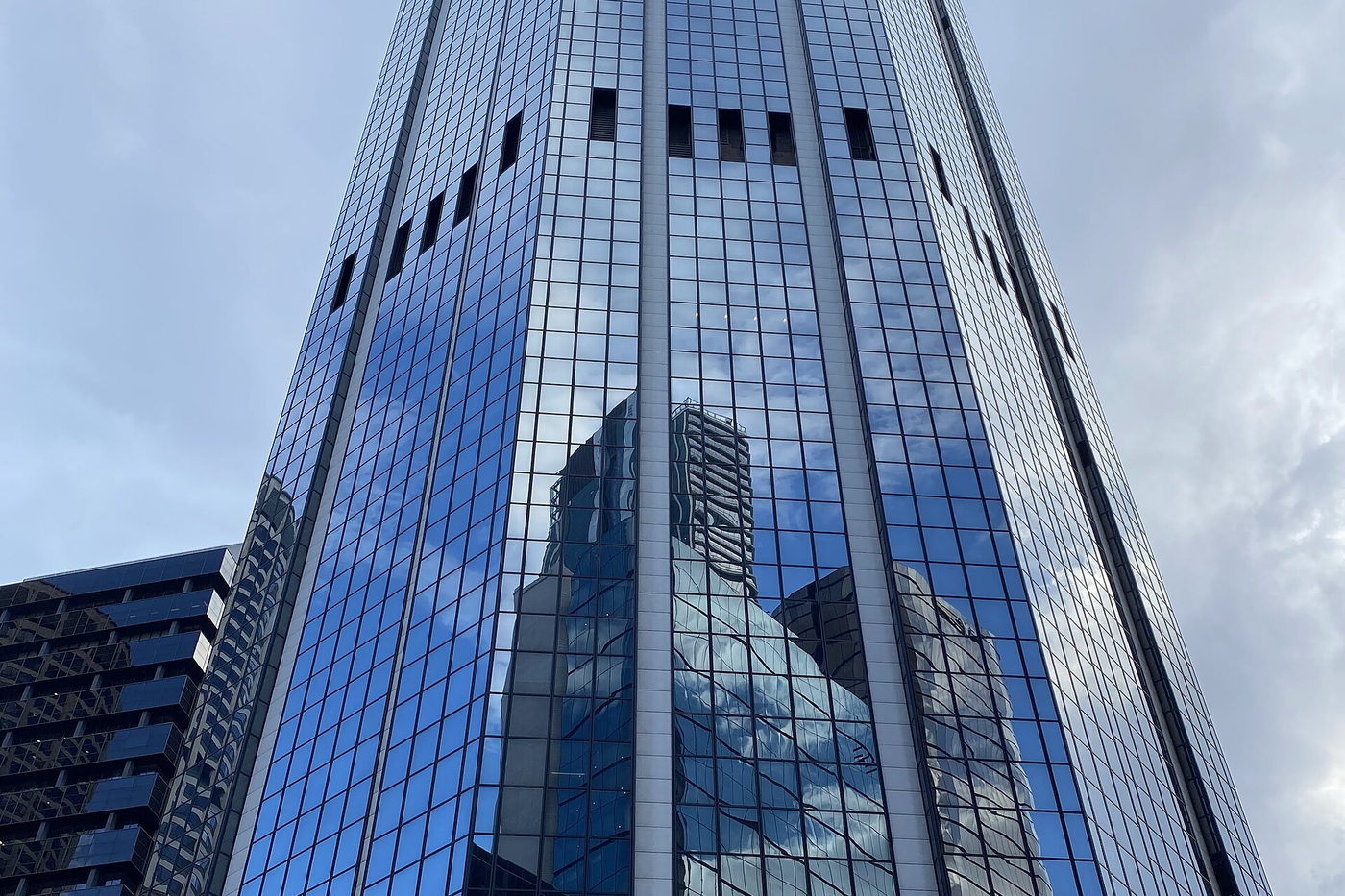 Blue glass office tower rising above the street