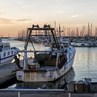 A working boat moored in a marina at dusk.