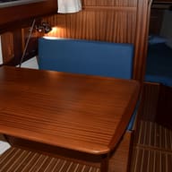 A varnished mahogany table and a blue cushion in a yacht saloon.
