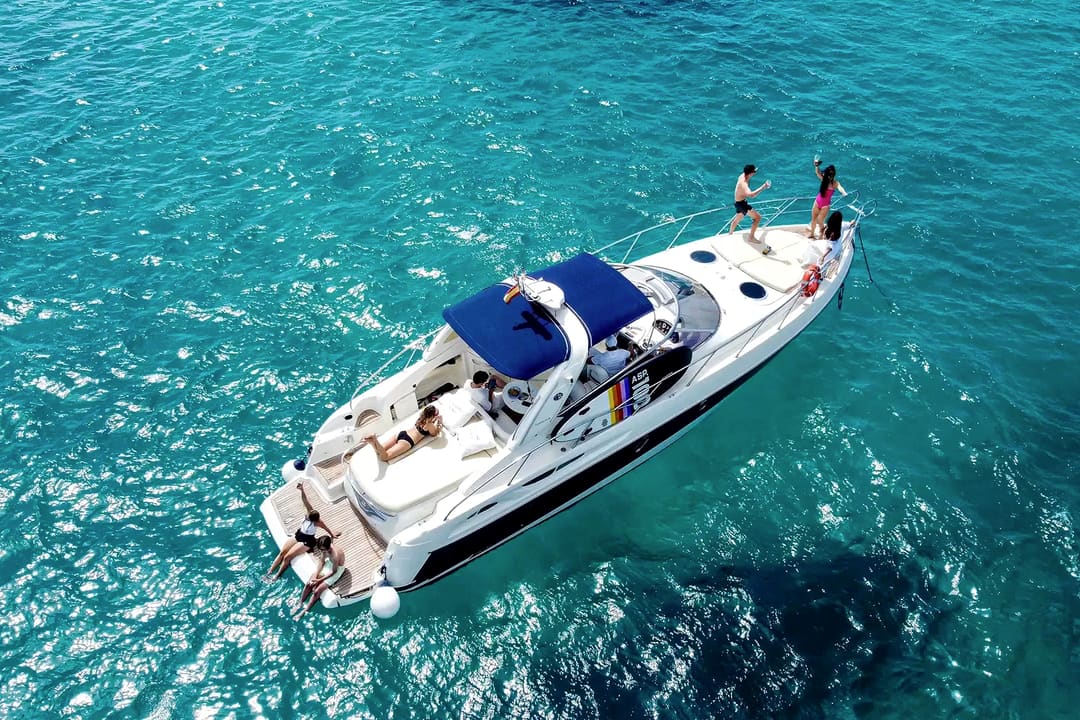 A white motor yacht seen from above on clear turquoise water.