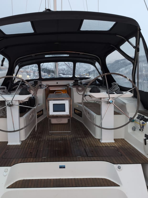 The cockpit of a sailing yacht under a bimini, with twin wheels.