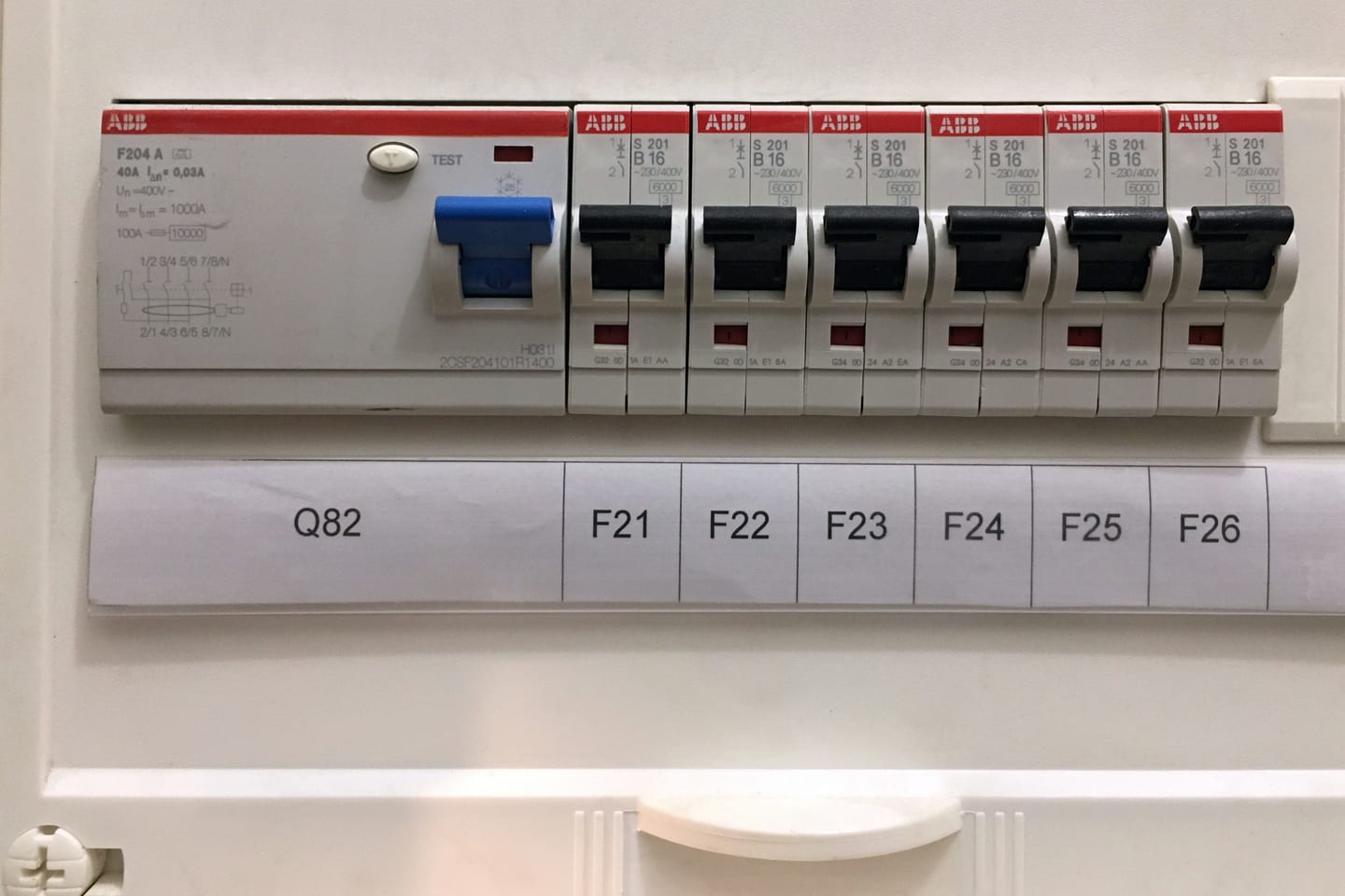 A row of miniature circuit breakers beside a residual current device in a consumer unit, each way numbered on the label strip below.