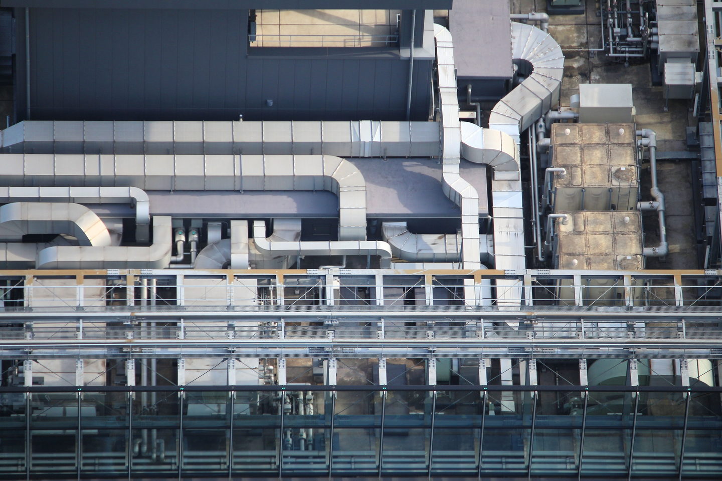 Rooftop air conditioning units and ventilation ducts spread across a flat roof under a clear sky.