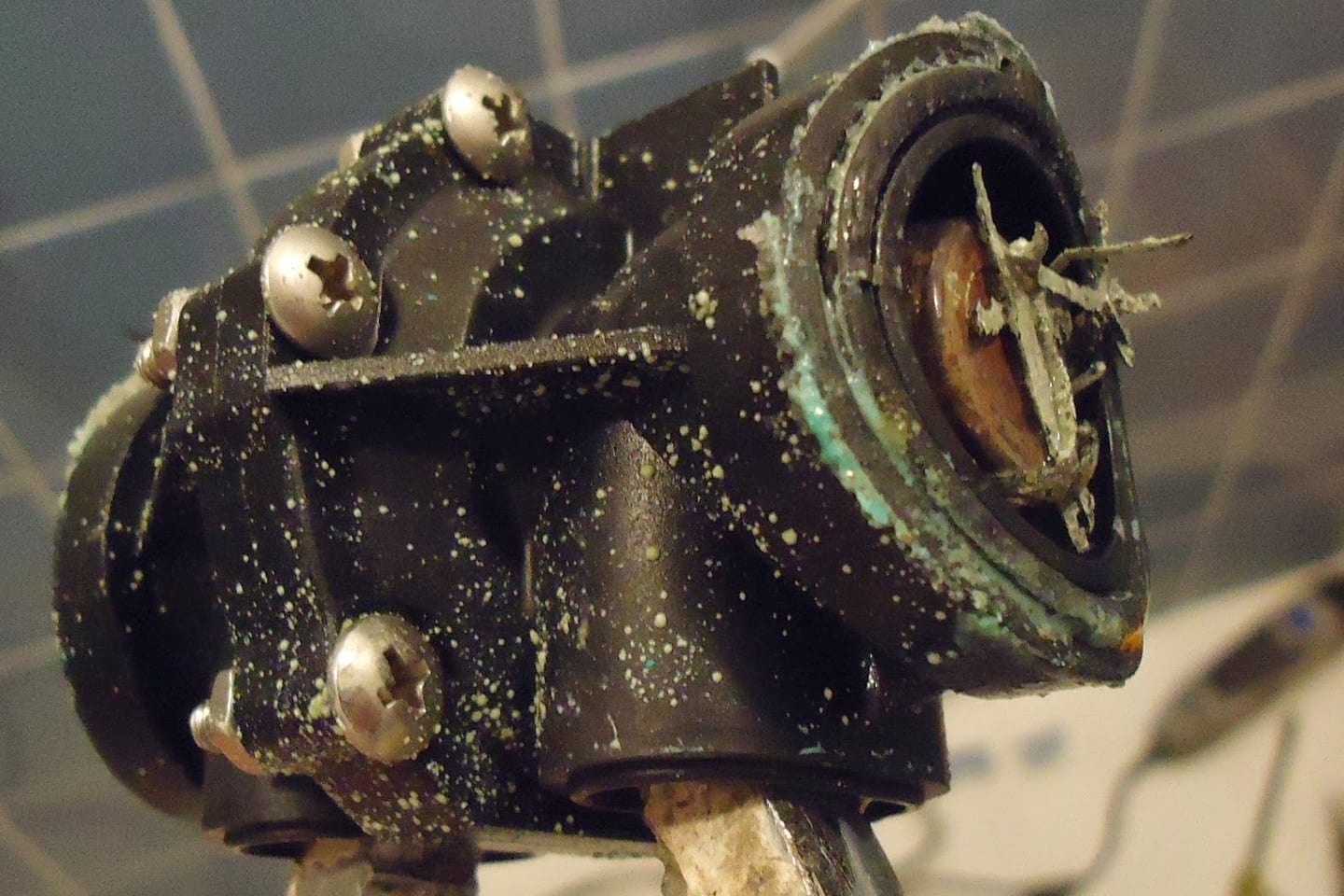 A shower diverter valve held clear of the wall with its seals and retaining nut exposed