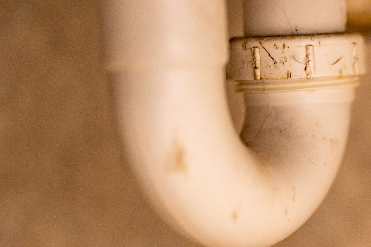 A close view of a plastic trap arm and its slip-joint nut beneath a sink