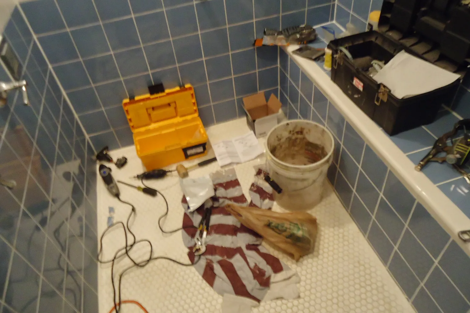 Shower-valve replacement tools and parts laid out on the protected work surface
