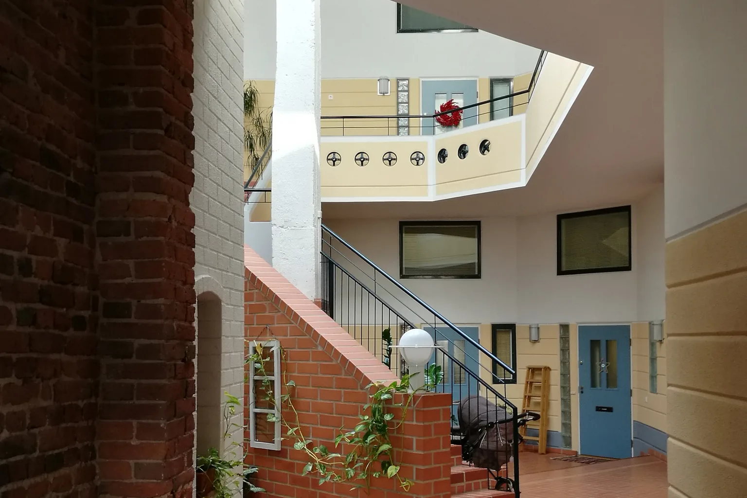 Brick-floored apartment entrance with a stairway and painted doors