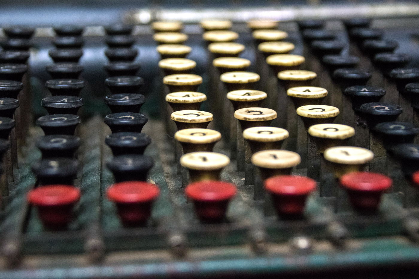 The keyboard of a mechanical calculator in close view, its rows of red, cream and black number keys filling the frame.