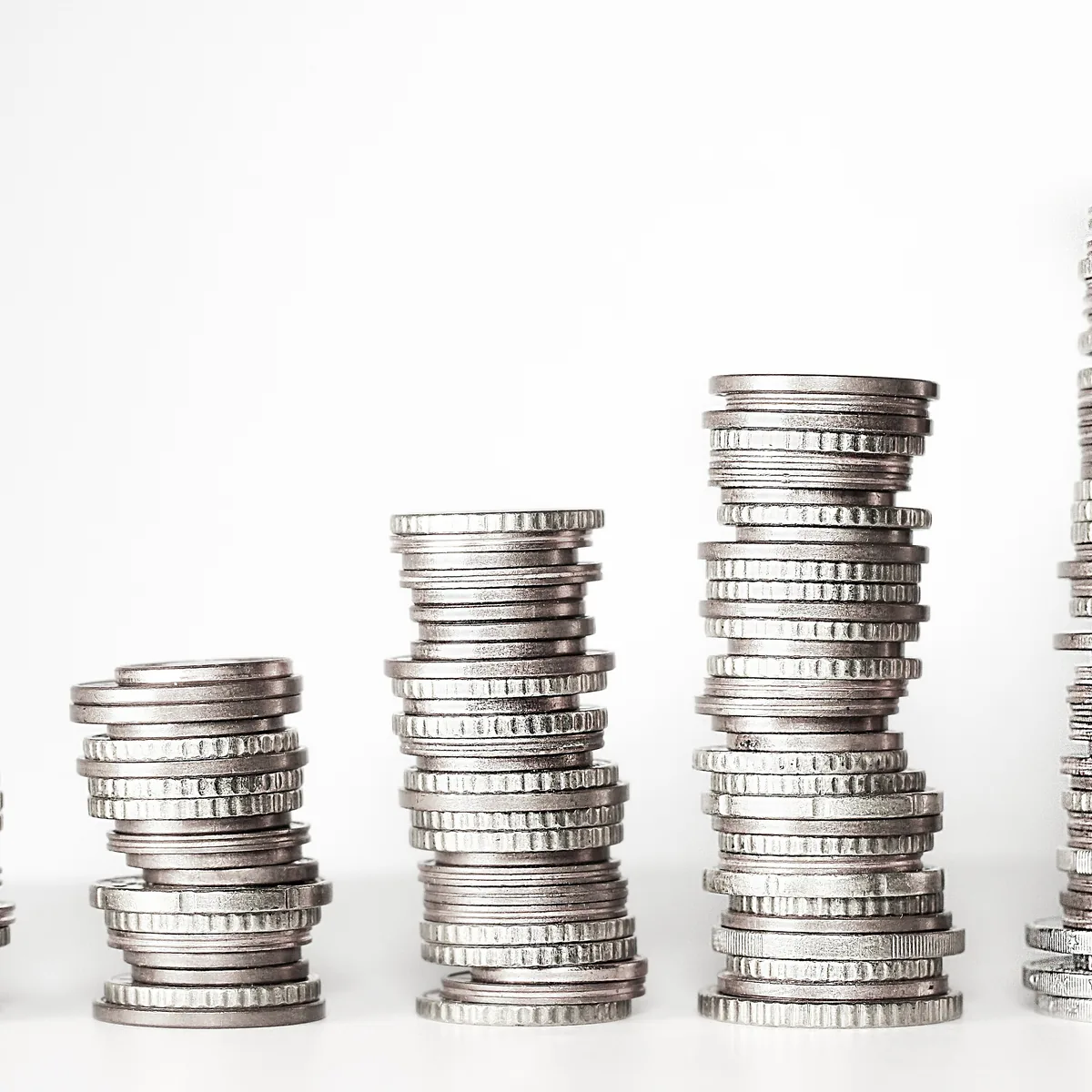 Three rising stacks of coins on a pale surface