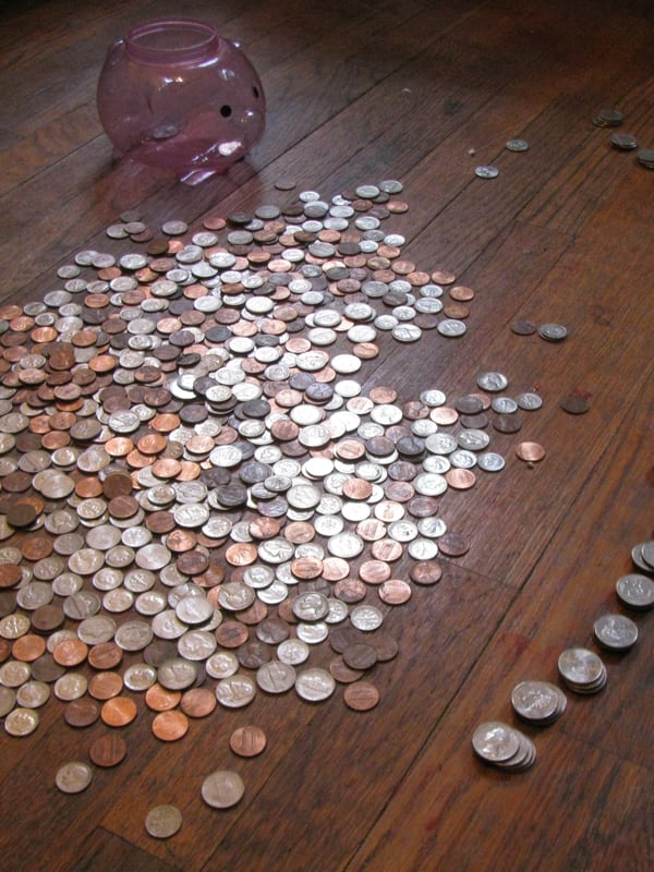 Coins tipped out of a piggy bank and spread across a wooden floor