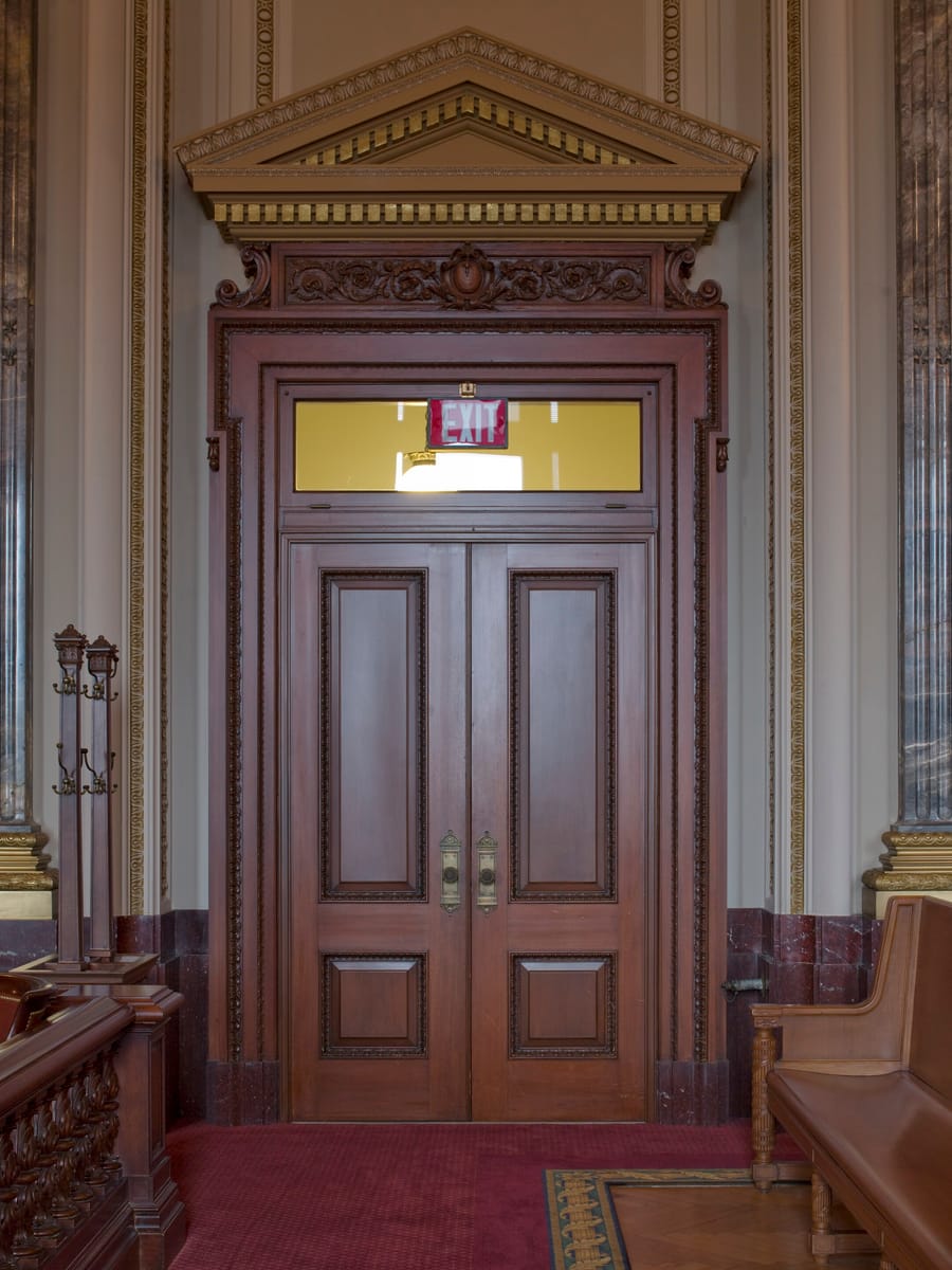 Tall panelled double doors under a carved pediment at a courtroom entrance.