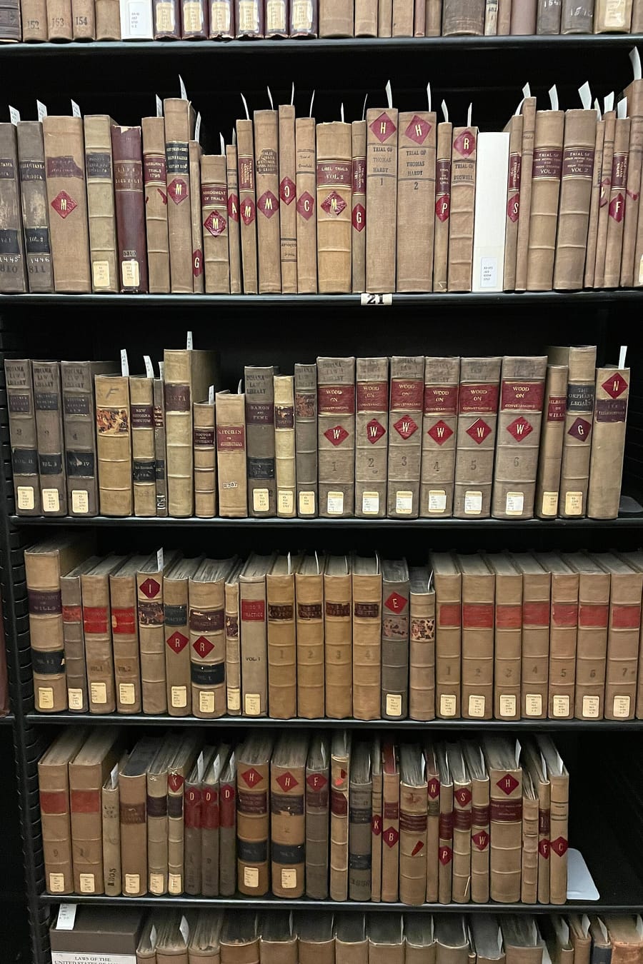 A tall shelf of old leather-bound law books with worn spines and red labels.