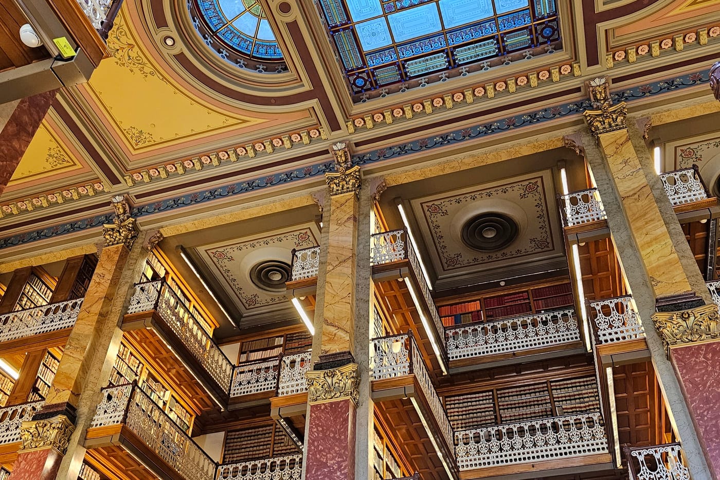 Looking up at the ornate painted ceiling and gilded balconies of a historic law library.