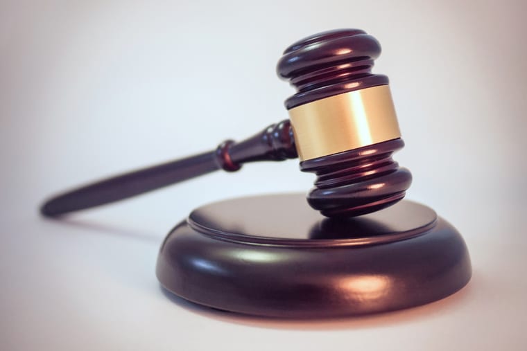 A wooden gavel resting on its block on a bare desk.