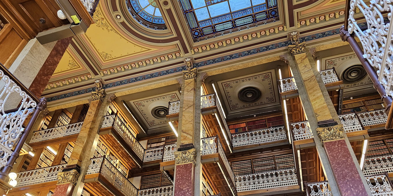 Tiered galleries of bound law reports rising overhead, rail after rail of matching spines.