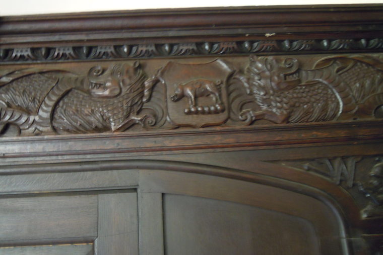 Deeply carved oak panelling showing heraldic animals in relief.