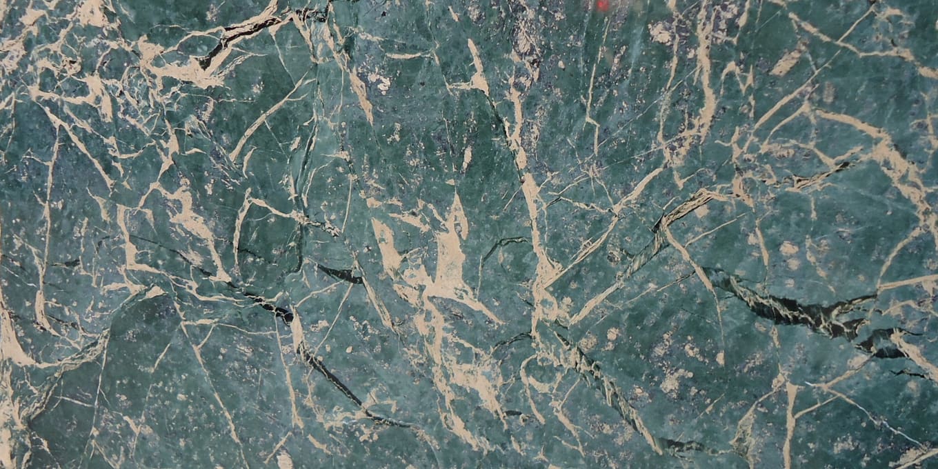 A slab of dark green marble with pale veining running across it.